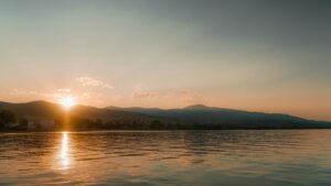 Sunrise over calm water with distant hills